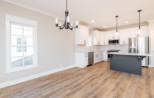 kitchen with tasteful backsplash, a chandelier, ornamental molding, stainless steel appliances, and a sink