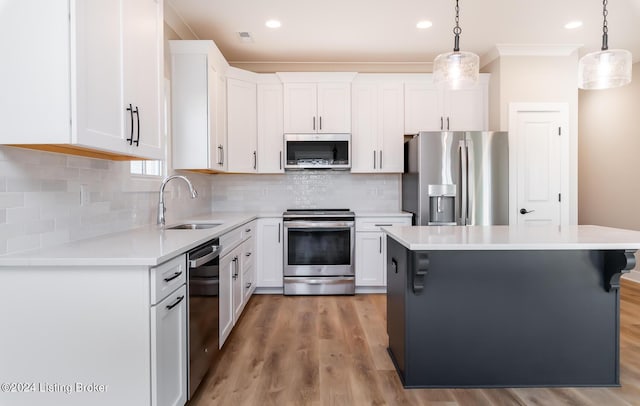 kitchen with a sink, stainless steel appliances, white cabinets, light countertops, and hanging light fixtures
