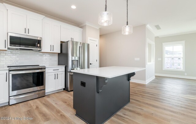 kitchen featuring ornamental molding, appliances with stainless steel finishes, tasteful backsplash, and light hardwood / wood-style floors