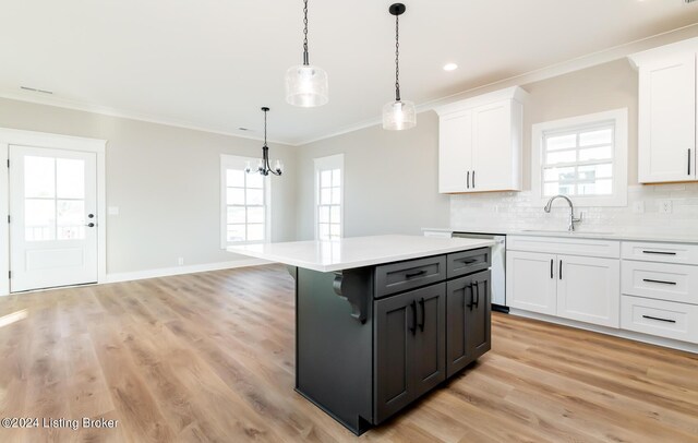 kitchen featuring ornamental molding, white cabinets, light countertops, and a sink