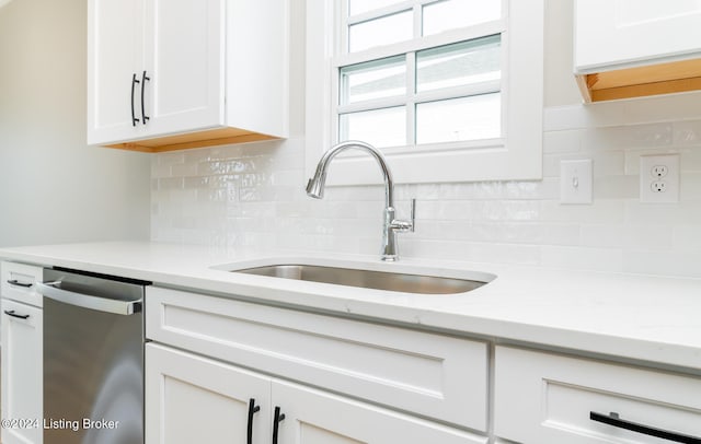 kitchen featuring white cabinetry, backsplash, sink, light stone countertops, and stainless steel dishwasher