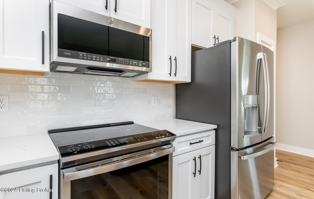 kitchen featuring light stone countertops, appliances with stainless steel finishes, light hardwood / wood-style floors, white cabinetry, and decorative backsplash