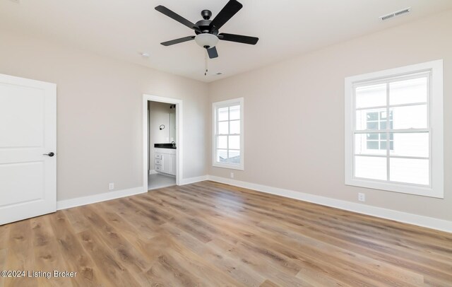 unfurnished bedroom featuring visible vents, light wood-style flooring, ensuite bath, and baseboards