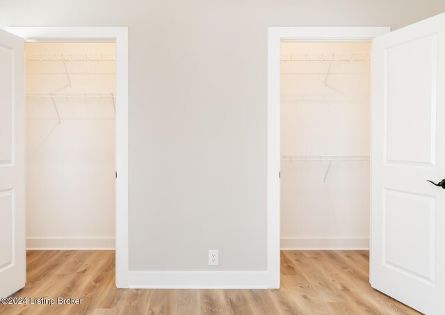unfurnished bedroom featuring a walk in closet, light wood-style flooring, baseboards, and a closet