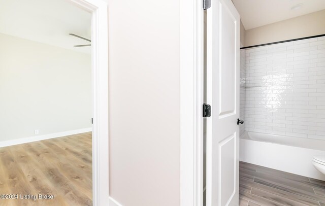 full bathroom featuring baseboards, toilet, shower / washtub combination, and wood finished floors