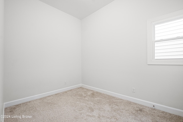 carpeted empty room featuring vaulted ceiling