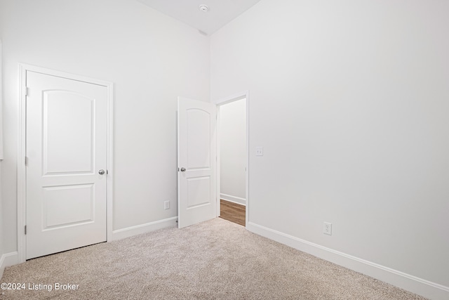 unfurnished bedroom featuring high vaulted ceiling and carpet floors