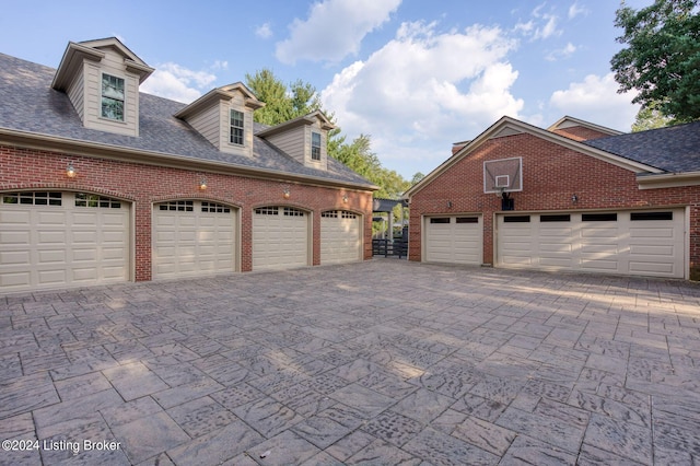 view of property exterior with a garage, brick siding, and roof with shingles