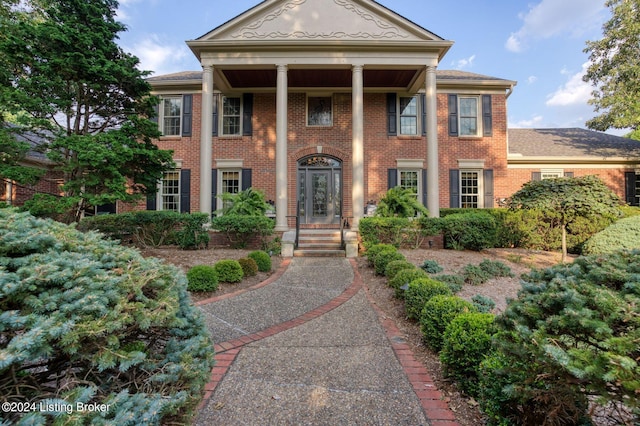 neoclassical home with brick siding and roof with shingles