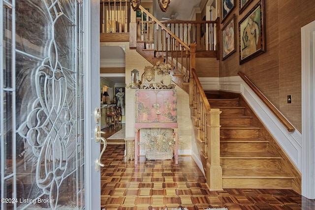 foyer with crown molding and stairway