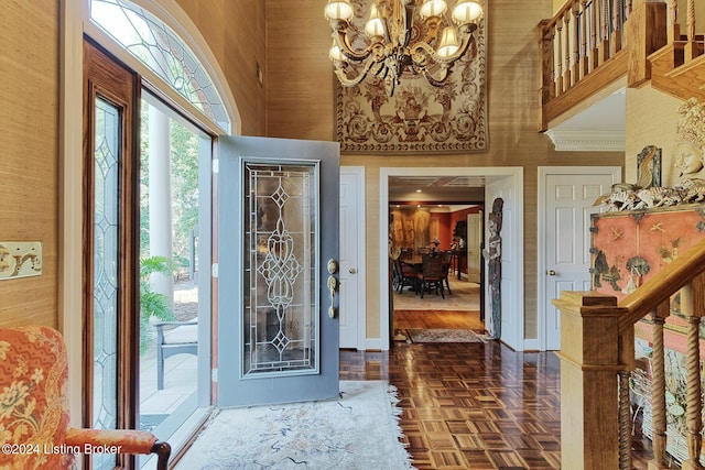 entryway featuring a towering ceiling, baseboards, and a chandelier