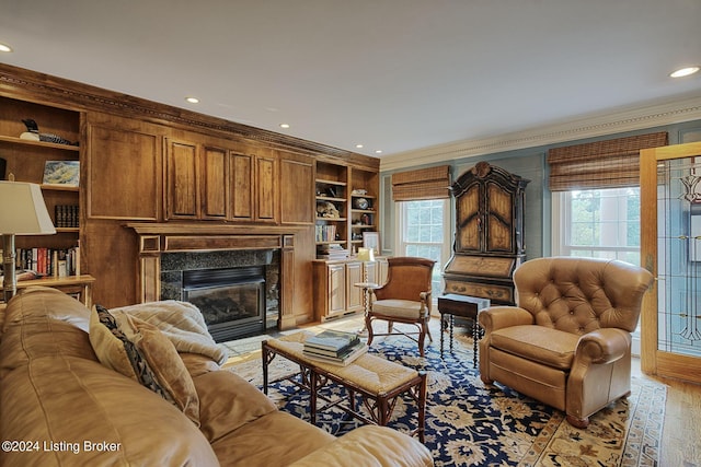 living area with built in features, crown molding, recessed lighting, a high end fireplace, and light wood-type flooring