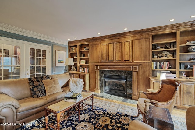 living area with a high end fireplace, crown molding, light wood-style floors, and recessed lighting