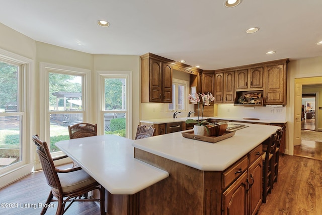 kitchen featuring recessed lighting, a breakfast bar, light countertops, a center island, and dark wood finished floors