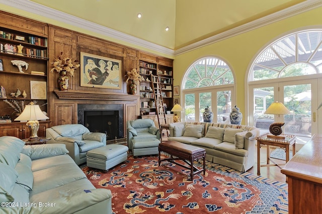 living room with built in features, crown molding, a fireplace, a high ceiling, and wood finished floors