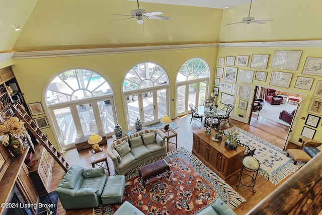 living area featuring a ceiling fan, a towering ceiling, and wood finished floors