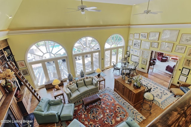 living room with ceiling fan, a high ceiling, and wood finished floors