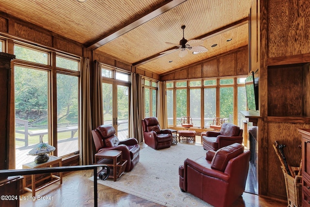 living room with lofted ceiling with beams, wooden ceiling, ceiling fan, and wood walls