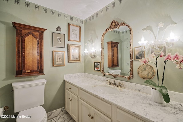 bathroom with marble finish floor, vanity, and toilet