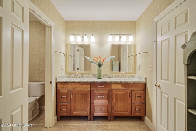 bathroom with double vanity, a sink, and toilet