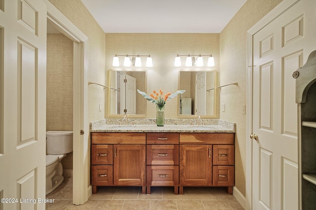 bathroom featuring toilet, double vanity, and a sink