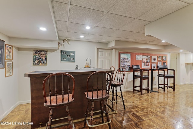 bar featuring a drop ceiling, wet bar, baseboards, and recessed lighting