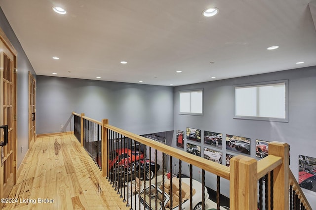 hallway featuring baseboards, an upstairs landing, wood finished floors, and recessed lighting