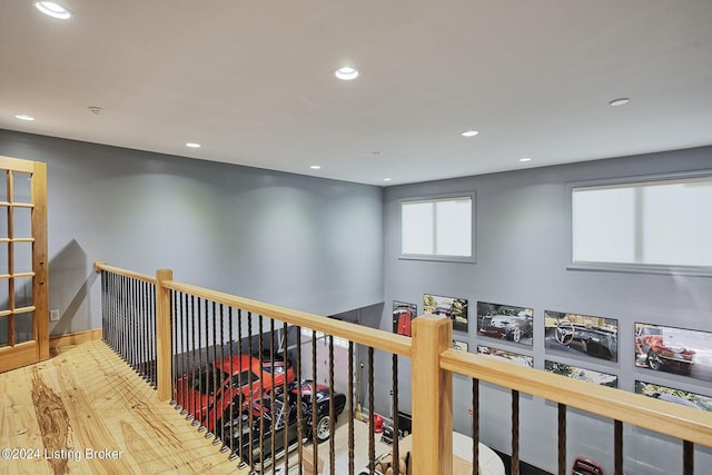 hallway with an upstairs landing, wood finished floors, and recessed lighting