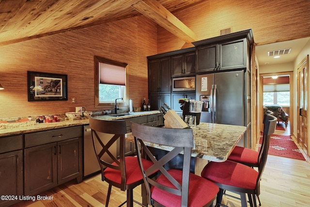 kitchen with visible vents, stainless steel appliances, a sink, light wood-style floors, and a breakfast bar area