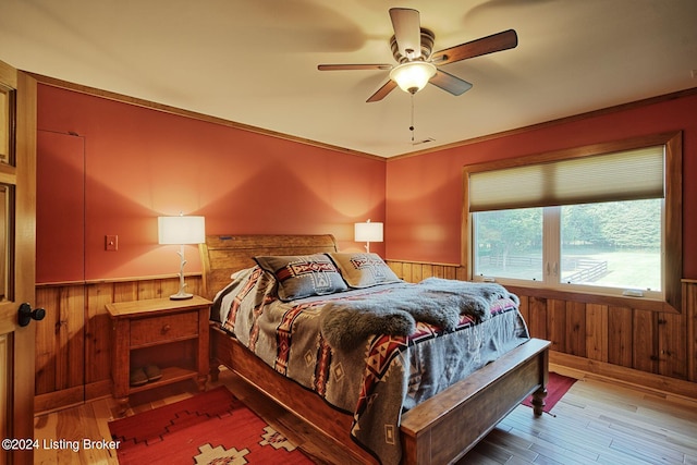 bedroom with wood finished floors, wooden walls, and wainscoting