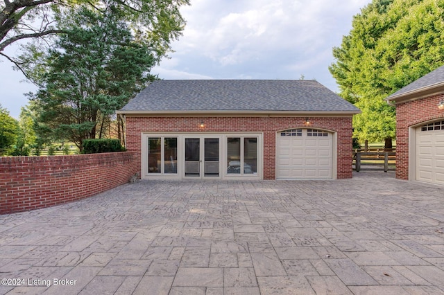 garage featuring decorative driveway and fence