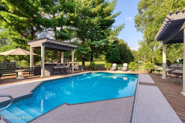 pool with outdoor dry bar, outdoor dining area, a pergola, and a wooden deck