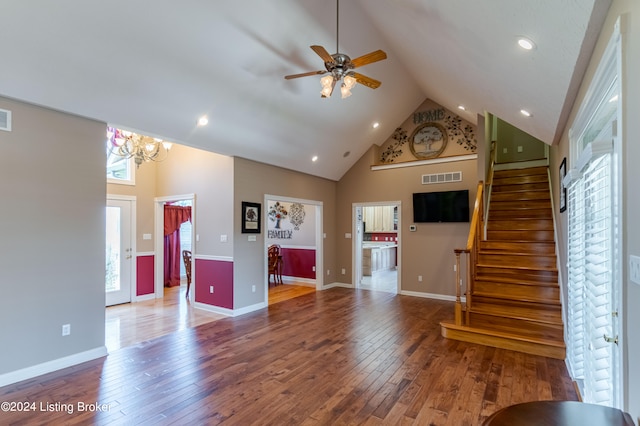 unfurnished living room with a wealth of natural light, high vaulted ceiling, ceiling fan with notable chandelier, and wood-type flooring