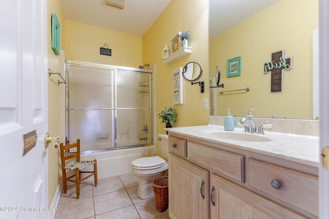 full bathroom with a textured ceiling, vanity, tile patterned flooring, toilet, and enclosed tub / shower combo