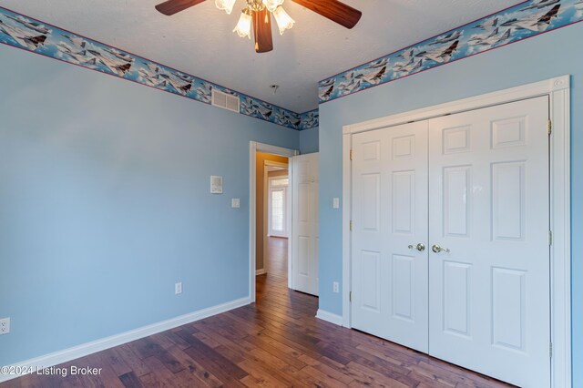 unfurnished bedroom featuring a closet, ceiling fan, dark hardwood / wood-style floors, and a textured ceiling