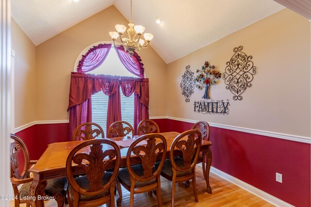 dining area with lofted ceiling, a notable chandelier, and light hardwood / wood-style floors