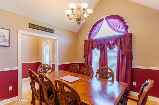 dining space featuring light wood-type flooring, lofted ceiling, and an inviting chandelier