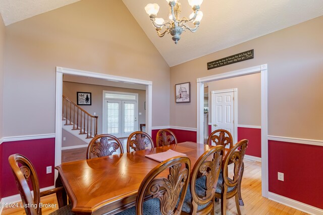 dining room featuring high vaulted ceiling, a notable chandelier, and light wood-type flooring