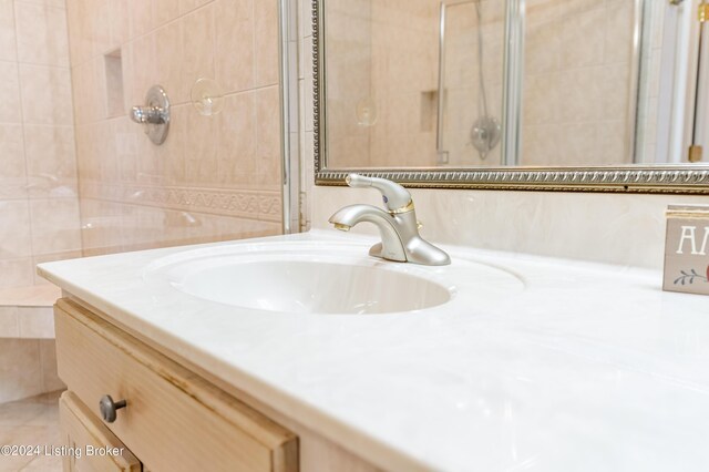 bathroom with tiled shower, vanity, and tile walls