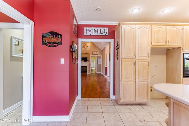 kitchen featuring light hardwood / wood-style flooring, vaulted ceiling, ornamental molding, and oven