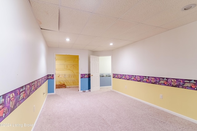 interior space with a paneled ceiling and carpet flooring