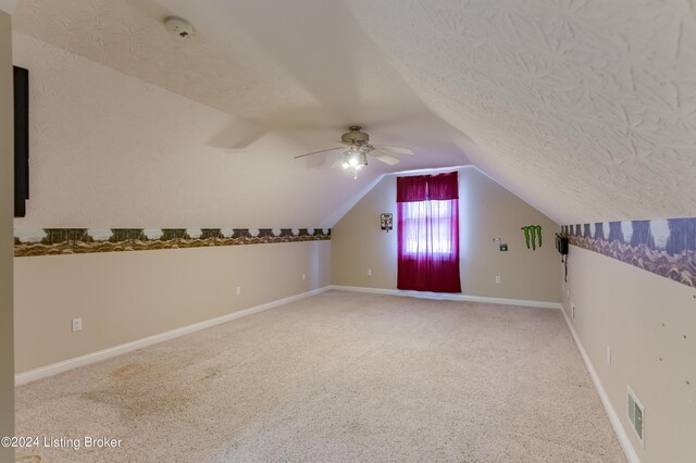 additional living space featuring lofted ceiling, carpet flooring, ceiling fan, and a textured ceiling