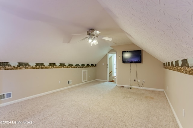 additional living space featuring lofted ceiling, a textured ceiling, ceiling fan, and carpet flooring