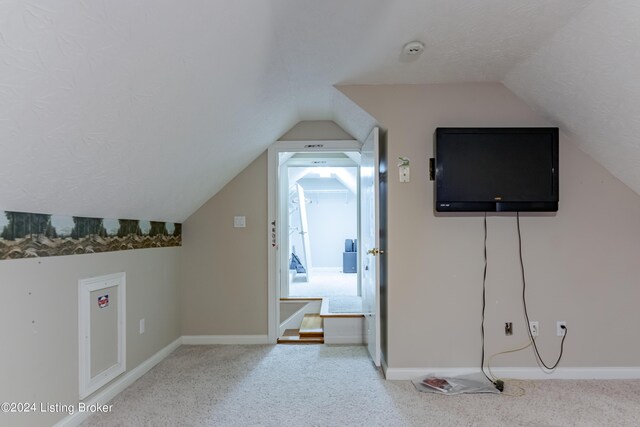 additional living space featuring lofted ceiling and carpet