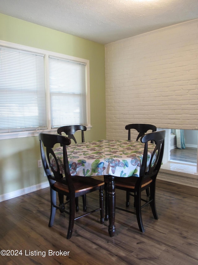 dining room featuring a textured ceiling, brick wall, and dark hardwood / wood-style floors