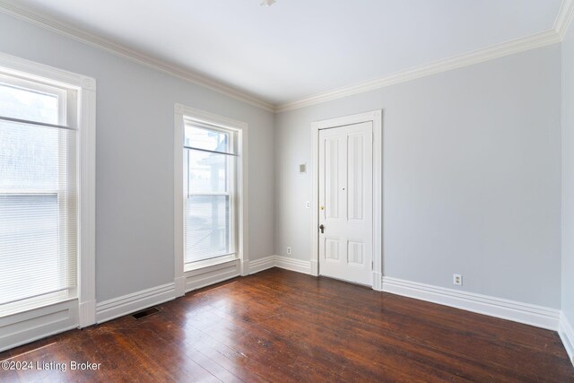 empty room featuring ornamental molding, dark wood-type flooring, and a healthy amount of sunlight