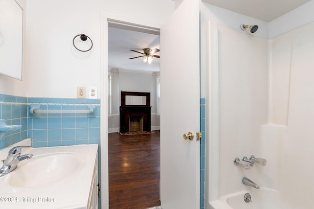 bathroom featuring ceiling fan, vanity, shower / bathing tub combination, tile walls, and hardwood / wood-style floors