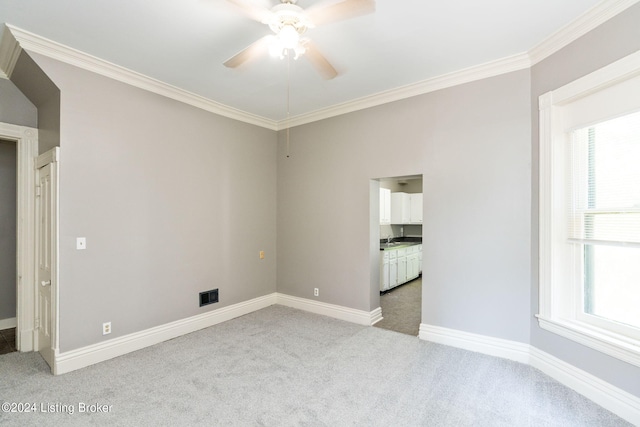 carpeted spare room featuring ceiling fan, plenty of natural light, and ornamental molding