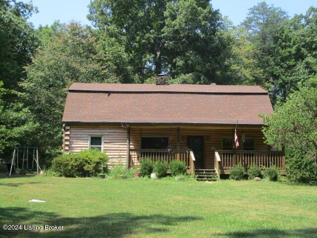 log cabin featuring log exterior, a porch, roof with shingles, and a front yard