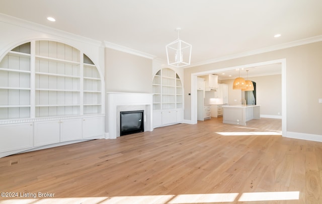 unfurnished living room with built in features, crown molding, and light wood-type flooring